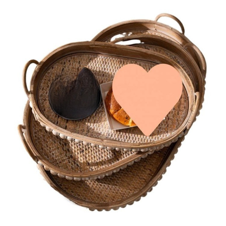 Nested oval rattan trays on white with two pasted shapes covering part of the weave, studded rim visible