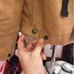 Close view of the khaki jacket hem with a snap-button tab held in a hand