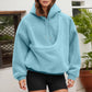 Woman wearing a light blue plush fleece hoodie with a pouch pocket and black shorts, front view