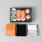 Sushi themed cotton crew socks folded into nigiri and maki shapes on a plate, playful novelty foodie gift