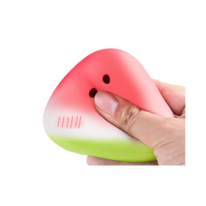 Watermelon shaped squishy toy squeezed flat between finger and thumb showing its slow give