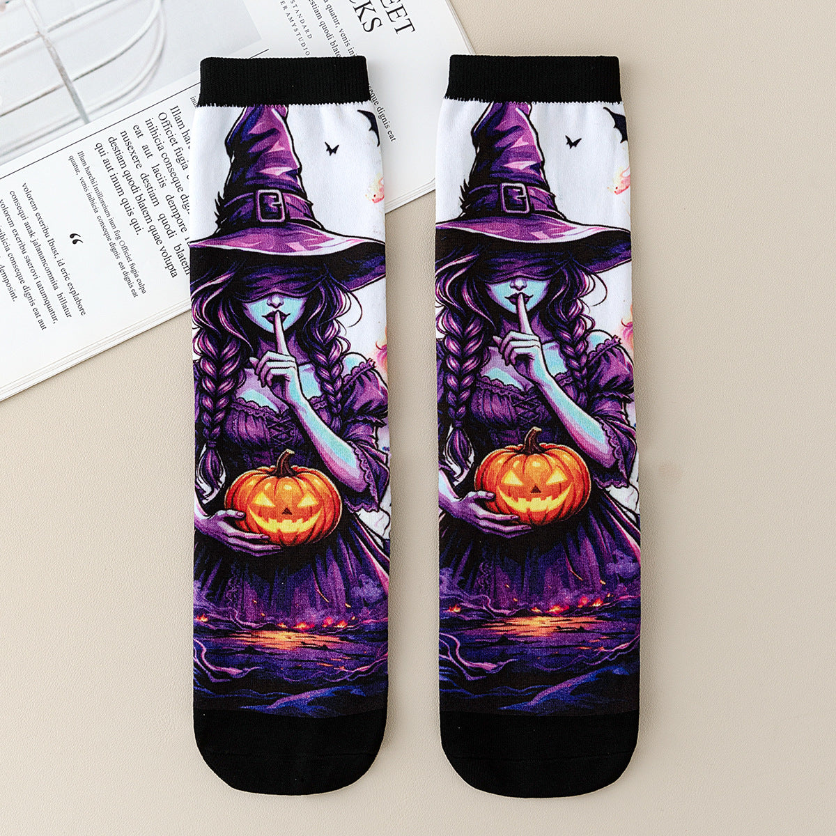 Pair of mid-calf socks printed with a purple witch holding a pumpkin and raising a finger to her lips