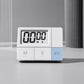 White digital kitchen timer with large LCD and three control buttons on a grey surface