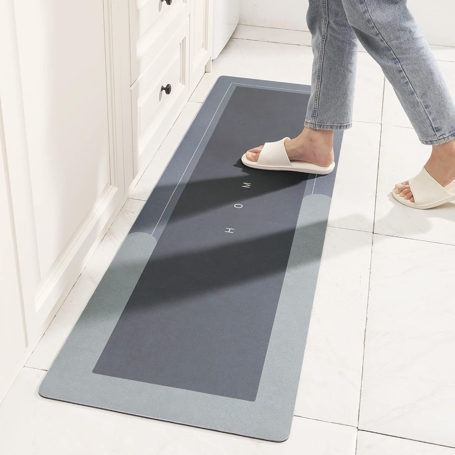 Flat quick dry bath mat angled on a bathroom floor beside a tub edge