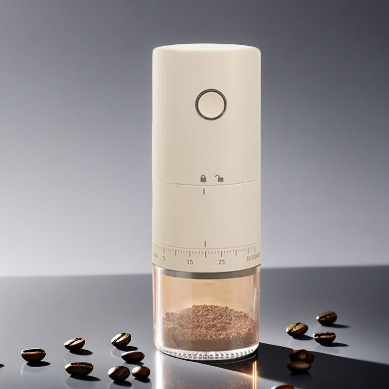 Cream electric coffee grinder with a round front button and numbered grind ring, coffee beans scattered on a dark surface