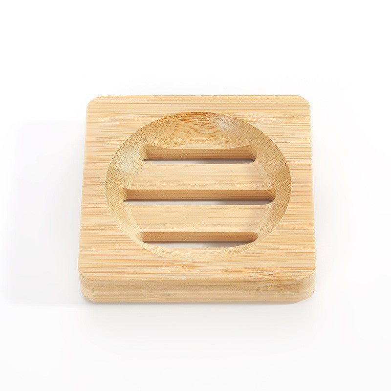 Square bamboo soap dish with a round shallow well and three drain slots on a white background