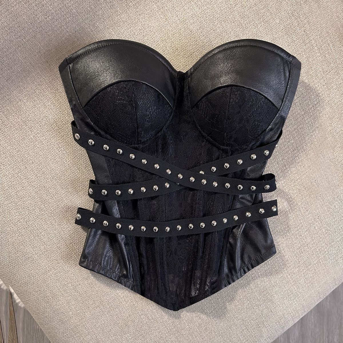 Full front of the black studded strapless bustier corset top with crossing waist straps