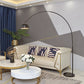 Metal dome shade of an arc floor lamp lit warm above a living room seat