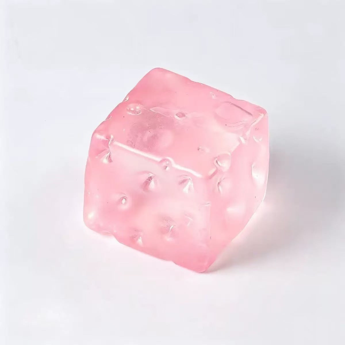 Translucent pink cheese cube squishy toy with moulded holes
