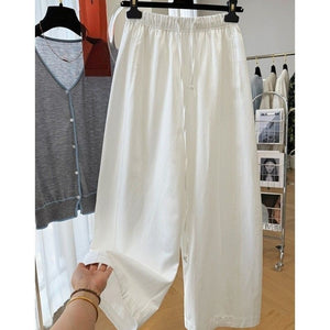 White ice silk wide leg pants on hanger with hand holding the soft fabric hem