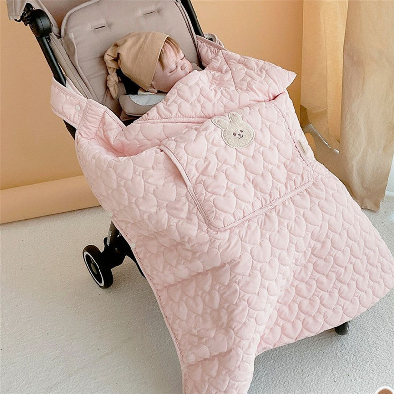 Caregiver pushing a stroller with the quilted cape covering the baby