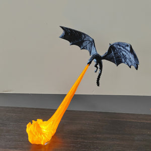 Black resin dragon figurine held above a lit orange flame stand against a plain wall
