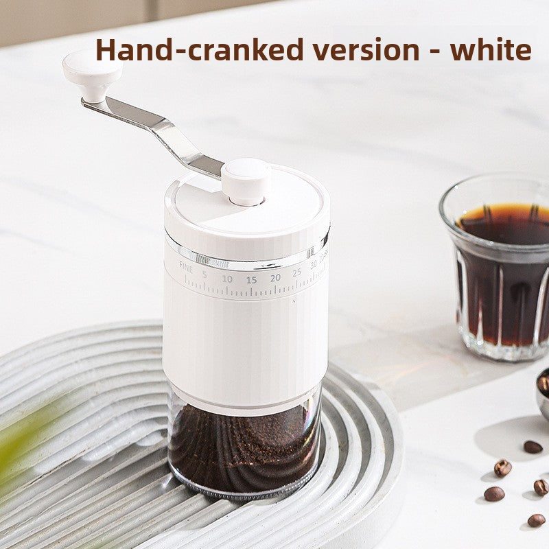 White hand-cranked coffee grinder with crank arm, fine to coarse scale and clear grounds chamber beside a coffee glass