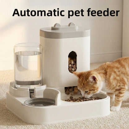 White plastic gravity pet feeder and water dispenser with a ginger cat eating kibble from the twin bowl base