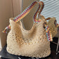 Beige open weave straw tote with multicolor woven strap standing by a mirror