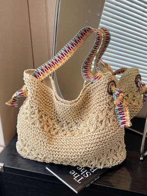 Beige open weave straw tote with multicolor woven strap standing by a mirror