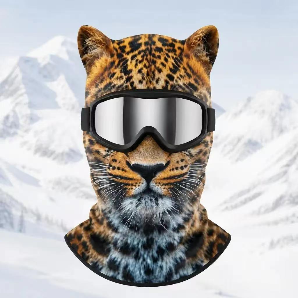 Leopard print fleece balaclava with ears and silver goggles on a snowy mountain