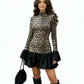 Woman in a leopard print mini dress with black ruffle hem and bell cuffs on a white background