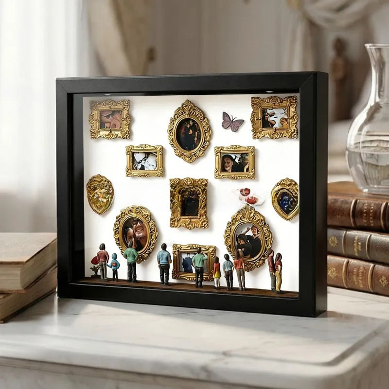 Black frame shadow box with a white backdrop showing gold miniature frames, a butterfly and figurines