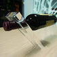 Close up of a transparent acrylic slanted wine bottle holder with a red wine bottle resting on it