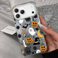Silver shimmer iPhone case printed with ghosts, pumpkins, bats, skulls and a witch hat, held in a hand