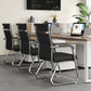 Row of three black ribbed leather cantilever chairs with chrome frames beside a wooden desk and laptop