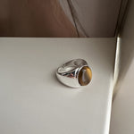S925 sterling silver ring with an oval tiger eye cabochon shown on a white surface