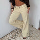 Beige trousers at the waist and hip with a folded cuff, model leaning against a white wall
