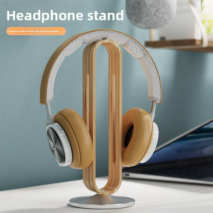 Silver wood grain aluminum headphone stand holding a pair of over ear headphones on a light desk
