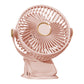 Pink clip fan on a plain background, three blades behind a round grille and gold hub ring