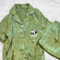 Close view of the green pajama shirt front with turn down collar, round buttons and PANDA pocket