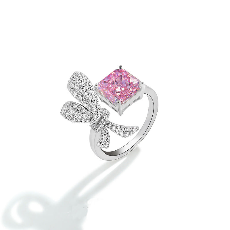 Bowknot ring in clear pave beside a radiant cut pink simulated diamond, adjustable band, white background