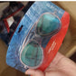 Grey green mirror aviator swim goggles held in a blister pack over a shipping box