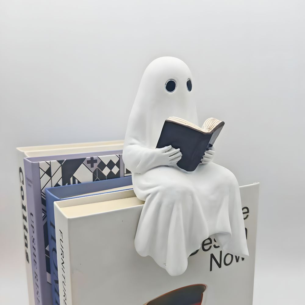 Reading ghost statue sitting on the corner of a pile of large books with its legs hanging over