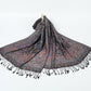 Black paisley jacquard scarf with a multicolor floral pattern, spread on white with black tassels