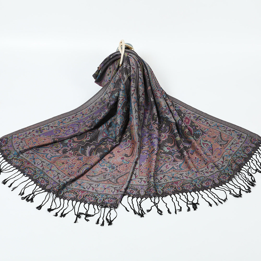 Black paisley jacquard scarf with a multicolor floral pattern, spread on white with black tassels