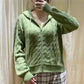 Woman wearing avocado green cable knit zip hooded cardigan over a plaid skirt, front view