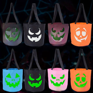 Eight canvas Halloween candy buckets with jack o lantern faces glowing green in the dark