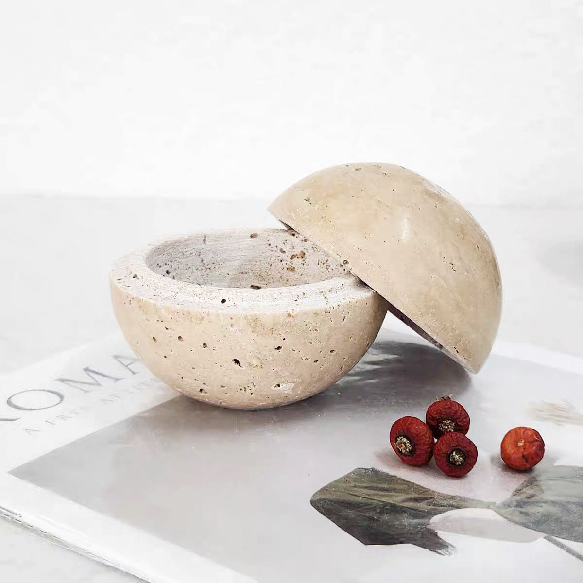 Beige travertine burner sphere opened into two hollow halves showing the inner bowl and rim