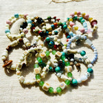 Handmade ceramic beads strand laid out, earth-tone glazed clay beads on cord