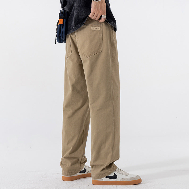 Khaki straight leg cotton pants in size 3XL, side view with a hand in the pocket and low sneakers