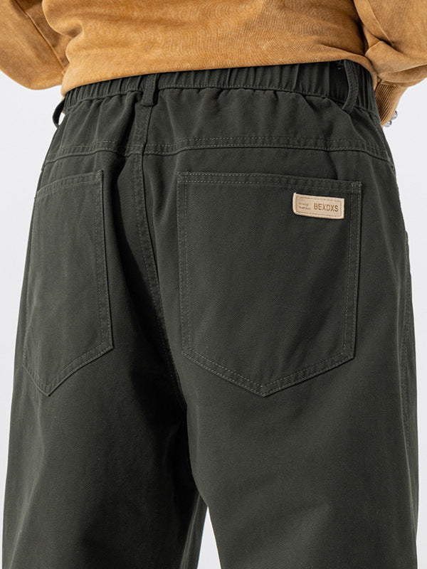 Close view of green pants with a back pocket, woven BEXDXS label and elasticated back waistband