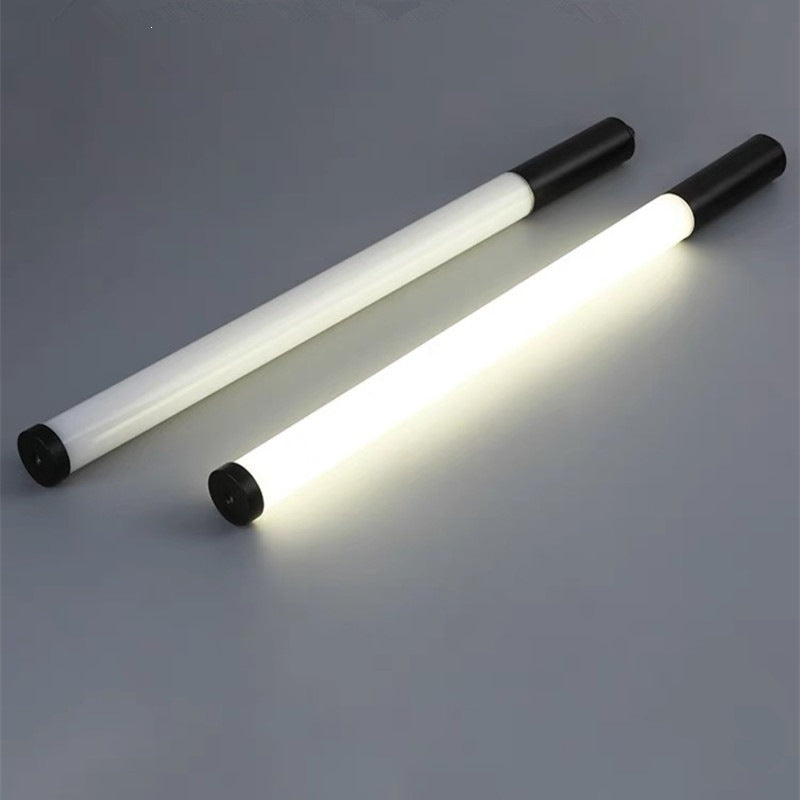 Two white LED tube lights with black end caps, one lit and one unlit, on a dark grey background