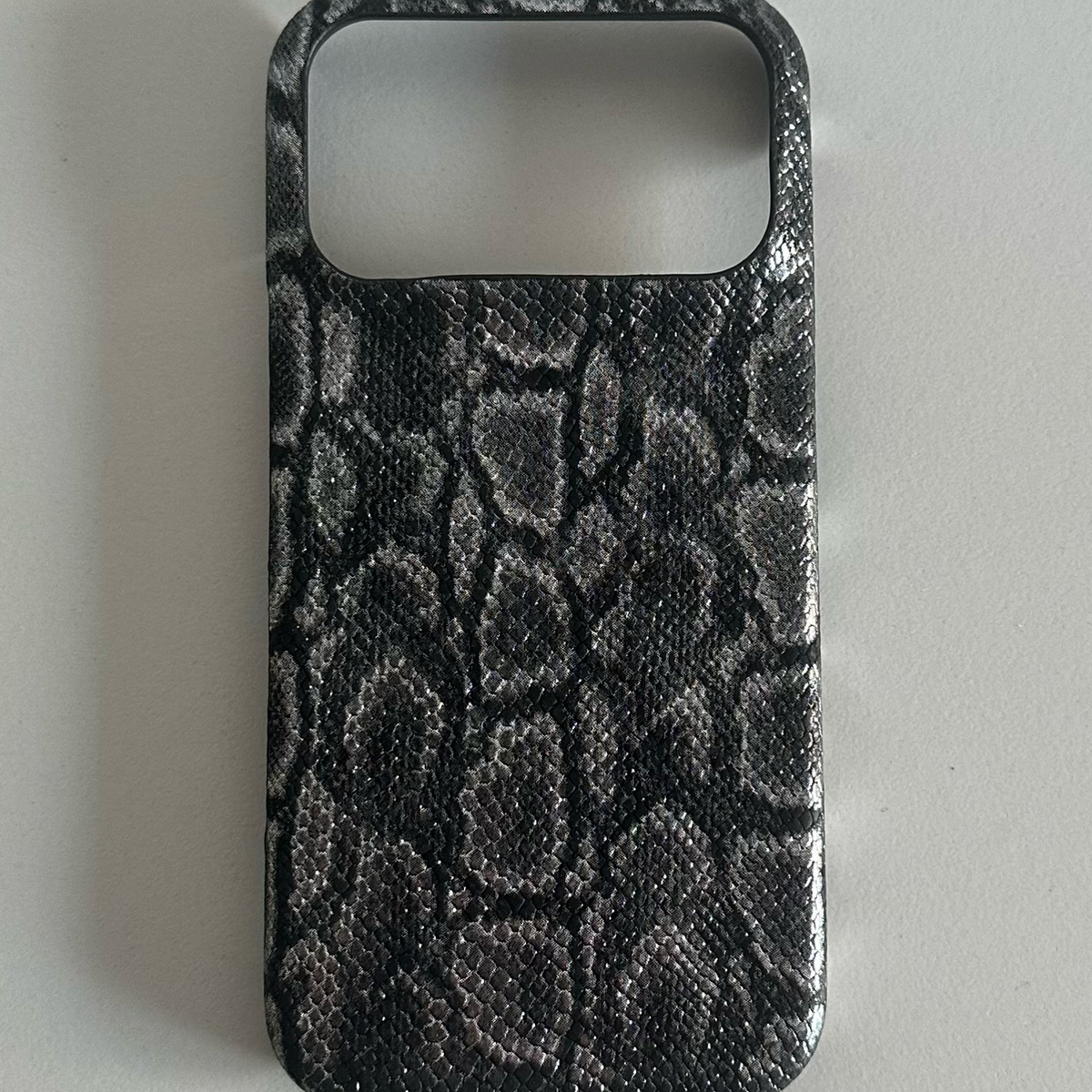 Black and grey snake print half-cover phone case on a grey surface, Black Python, iPhone X option