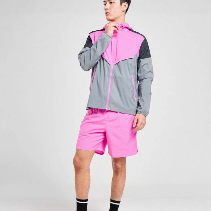 Man wearing a pink and grey colour block sports jacket with matching pink running shorts