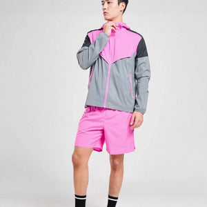 Man wearing a pink and grey colour block sports jacket with matching pink running shorts