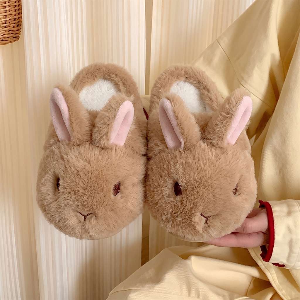 Pair of brown bunny plush slippers with pink lined upright ears held against a cream fabric background