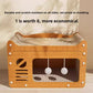 Cardboard cat scratcher box with a ridged top and three pom pom balls hanging in the front opening