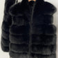 Black tiered vegan fur sleeveless vest on a wooden hanger with a wide V collar and open front