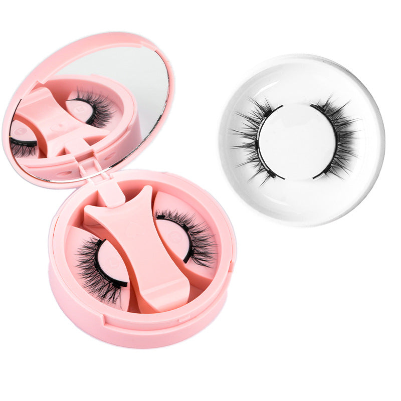 Pink round magnetic lash case with clip beside a wispy black magnetic lash in a ring